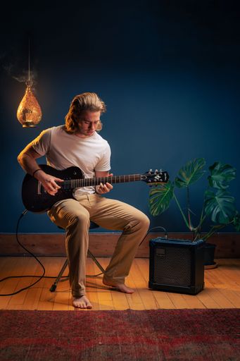 A vertical shot of a young caucasian man playing an electric guitar