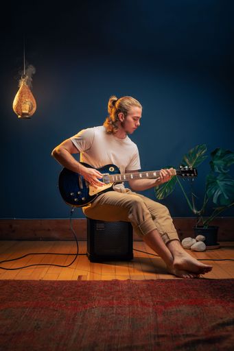 A vertical shot of a young caucasian man playing an electric guitar