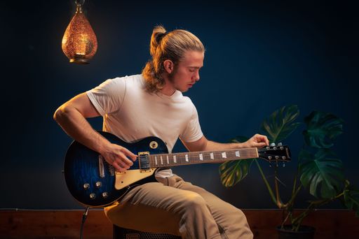 A young caucasian man tuning his electric guitar