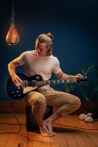 A vertical shot of a young caucasian man tuning his electric guitar