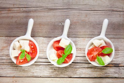 An overhead shot of a row of mini bowls with fresh Italian salad