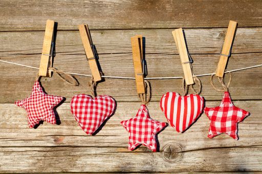 A row of star and heart-shaped toys hanging from a string with clothespins on a wooden background