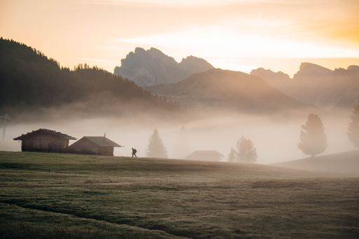 Rural houses and rocky mountains during a foggy sunrise in Seiser Alm, South Tyrol