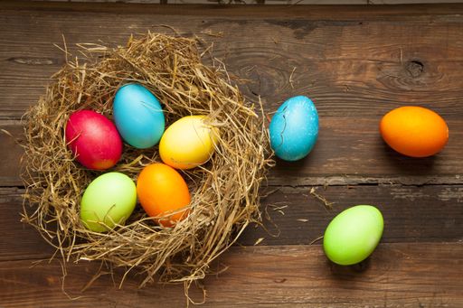 A top view of a bird's nest with colorful eggs on a wooden surface