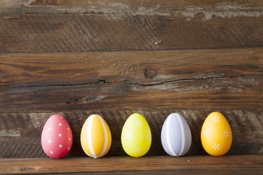 A row of colorfully decorated eggs with different patterns on a wooden table