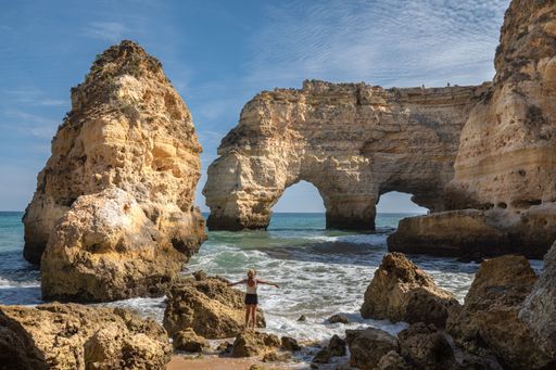 A tourist female posing near the Praia da Mesquita formations on the beach in the Algarve in Portugal