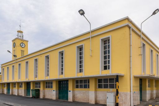 A fishing dock building in the city of Setubal, Portugal with a clock tower under gray sky