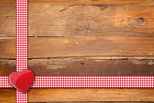 A top view of red ribbon and a heart decoration on a wooden background with space for text