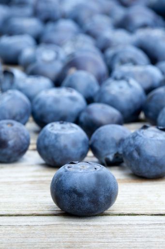 A vertical closeup shot of delicious and fresh blueberries on a wooden surface