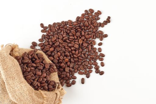 a top view of Colombian coffee beans in a burlap bag and on the floor isolated on the white background