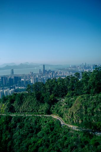 A vertical shot of the Victoria Peak with the view of Hong Kong in the background under a blue sky.