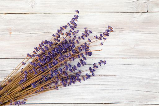 A high angle shot of branches with small purple flowers on a wooden surface