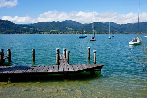 A beautiful view of Tegernsee lake with a wooden pier and boats in Bavaria, Germany