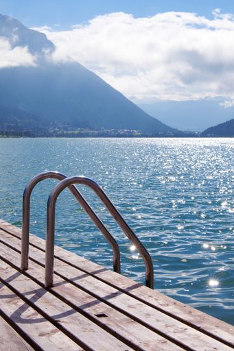 A beautiful vertical shot of a wooden dock on Lake Constance in Germany with mountains in the background