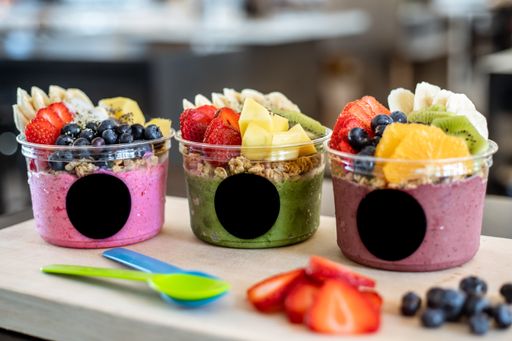 A closeup shot of plastic containers with colorful yogurts and fruits on top
