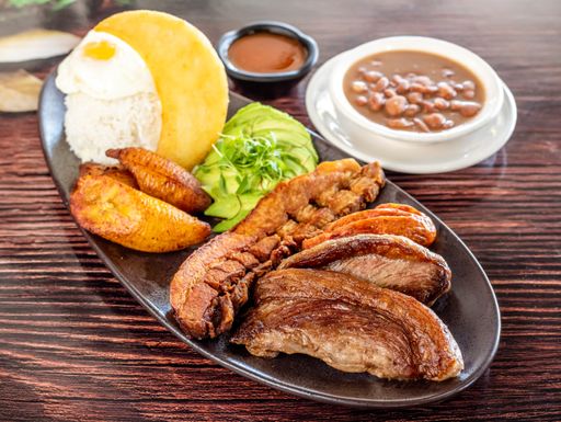 A plate of tasty grilled pork accompanied with fried potatoes and avocado