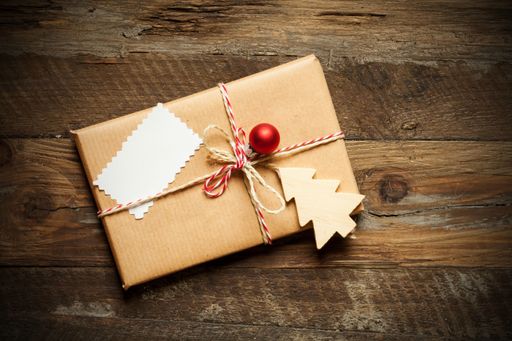 A top view of a Christmas gift wrapped in craft paper with a blank sign on a wooden background