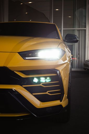 a vertical of Yellow Lamborghini Urus front view with headlights on