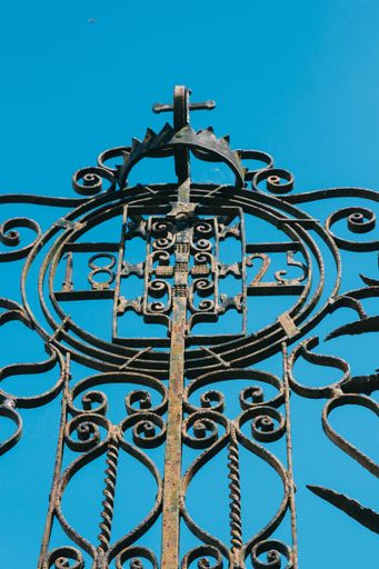 A low angle shot of a decorative metal fence with a background of the sky