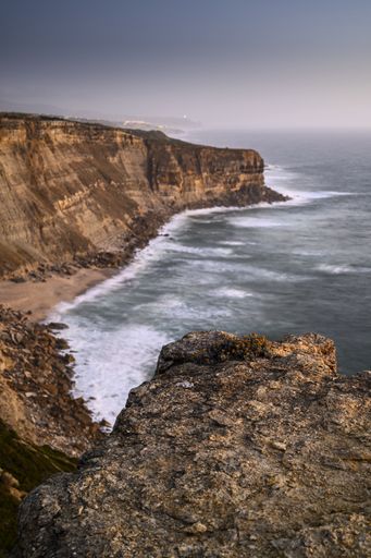 The beautiful wavy ocean hitting the beach surrounded by high cliffs