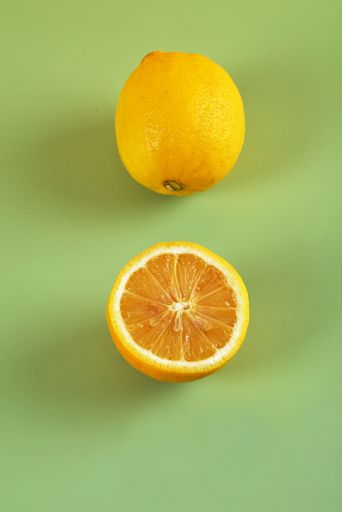 An isolated shot of a whole and a sliced lemon on a brown cloth