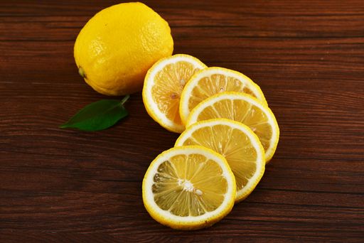 A closeup of a whole and slices of lemon on a wooden table