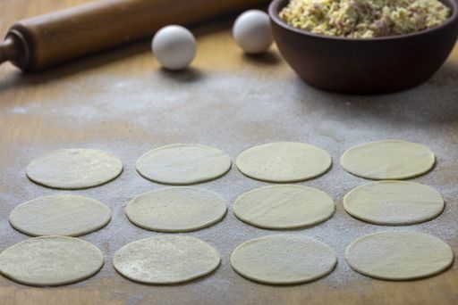 A high angle shot of round dough on a surface ready to be filled with vegetable fillings