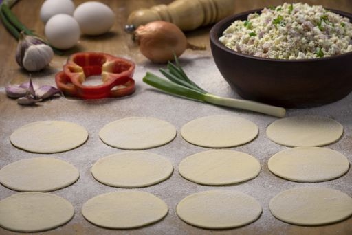 A high angle shot of round dough on a surface ready to be filled with vegetable fillings
