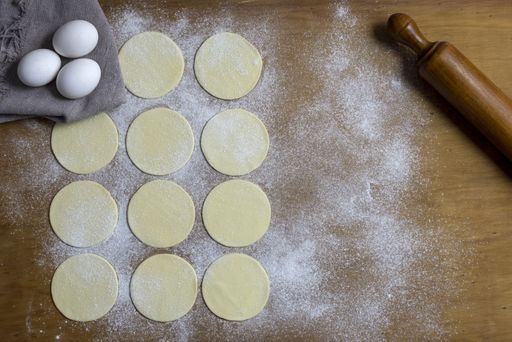 A high angle shot of round dough on a surface ready to be filled with vegetable fillings
