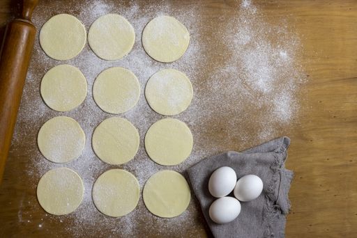 A high angle shot of round dough on a surface ready to be filled with vegetable fillings