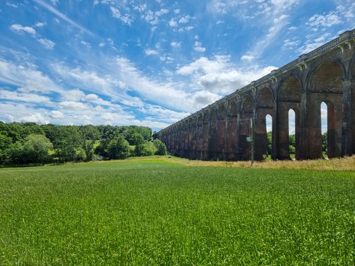 Bright sunny day in English Countryside next to Balcombe Ouse Valley Viaduct with green field and blue sky