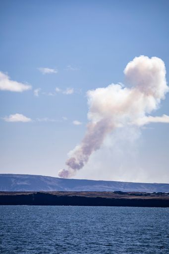 A vertical shot from the ocean of volcanic smoke in the blue sky