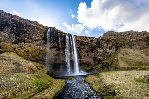 A gorgeous view of the Seljalandsfoss Waterfall in Iceland under a bright cloudy sky on a beautiful day