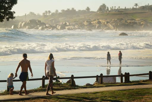 A family takes a stroll along the seafront at Camps Bay, Cape Town, South Africa
