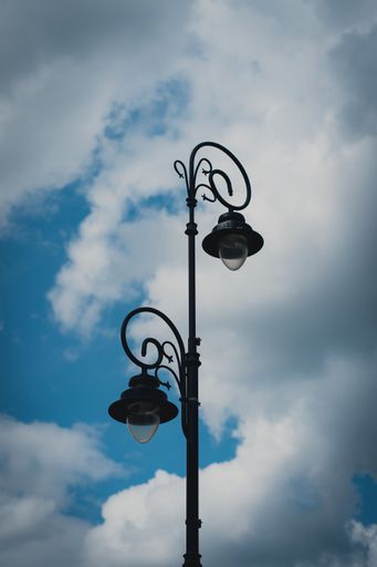 A vertical shot of lamp post against blue cloudy sky background