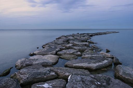 An aerial view of rocky path surrounded by water in sea