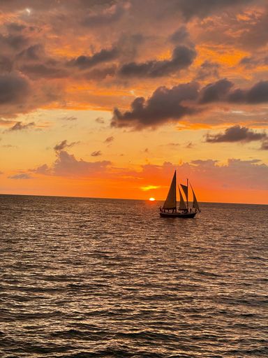 A vertical shot of a single boat in the sea at the sunset