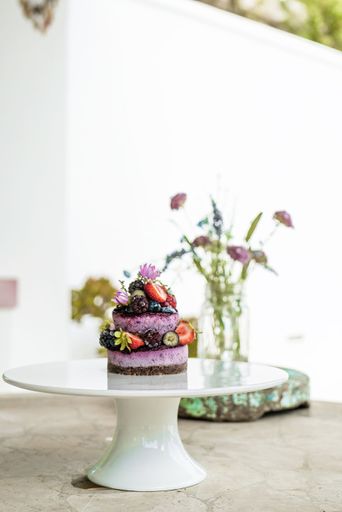 A vertical shot of healthy fruit cakes decorated with strawberries, acai berries, raspberries and wildflowers