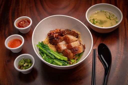 Tasty fried pork, noodles, and greens, served with a bowl of traditional soup and sauces