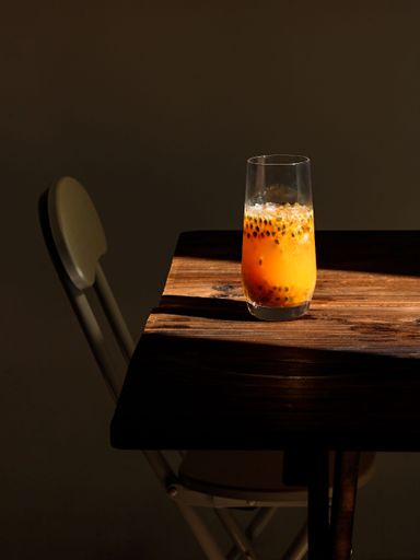 A vertical shot of a passion fruits smoothie on the wooden table in a sunlight