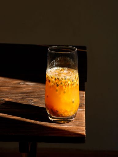 A vertical shot of a passion fruits smoothie on the wooden table in a sunlight