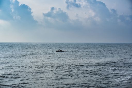 A beautiful shot of an ocean under cloudy sky with a person swimming in kayak