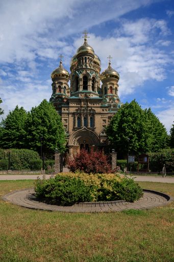 A vertical shot of St Nicholas Naval Cathedral surrounded by greenery under blue cloudy sky in Latvia