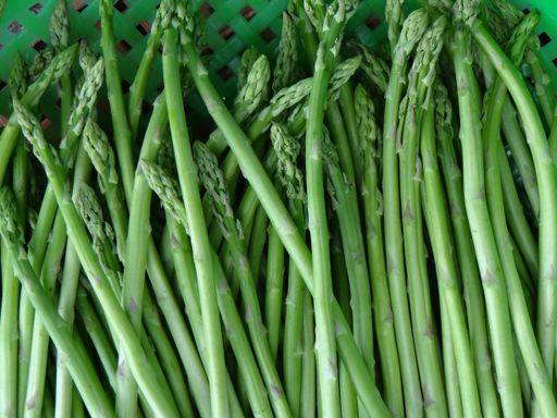 A high angle shot of green asparagus plants in a green basket
