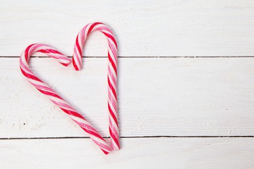 A top view of candy canes forming a heart on a white surface