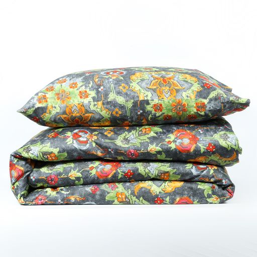 A closeup of a pillow on a folded blanket with a floral print isolated on a white background