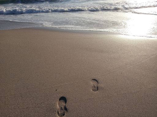 Two footsteps on a wet sand in the beach
