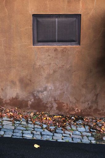 A vertical shot of a rusty ventilation window on a grunge wall