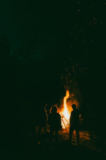 A silhouette of people in front of a bonfire at night