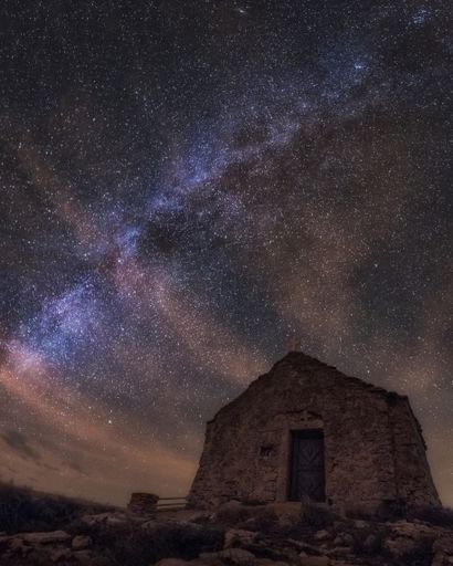An amazing low angle vertical shot of a chapel on top of Island Vis in Croatia under the milky way galaxy night sky